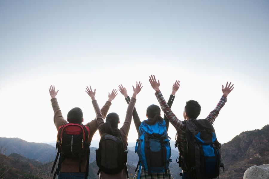 Four hikers with arms in the air
