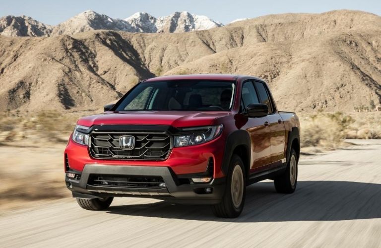 Front view of the 2022 Honda Ridgeline Red driving through a dusty road